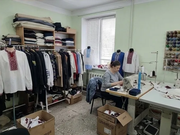 Майстриня за швейною машиною поруч із готовими вишиванками